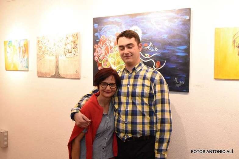 El joven artista junto a su madre, delante de uno de sus cuadros (Foto Antonio Alí)